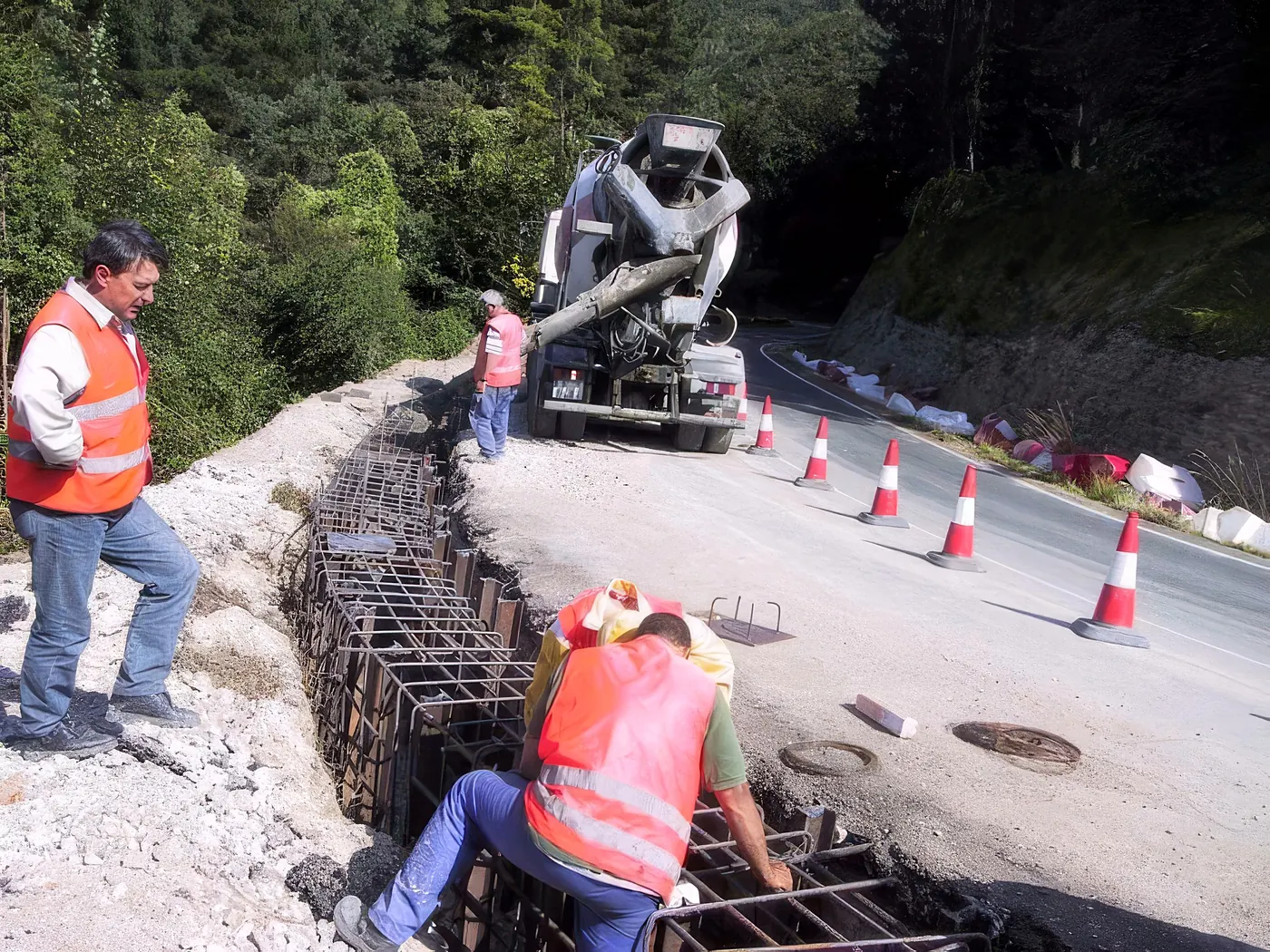 Operarios armando la viga del muro de carriles mientras llega la hormigonera
