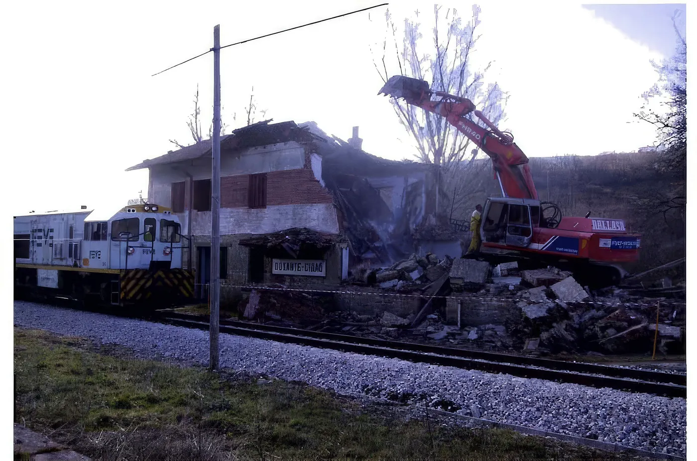 Retroexcavadora derribando un edificio junto a la vía del tren León-Bilbao