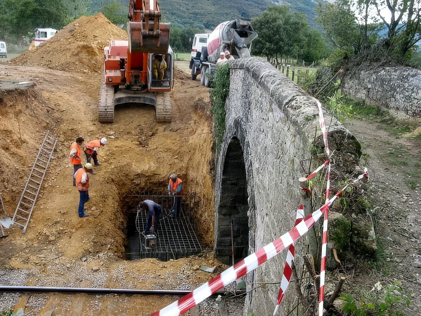 Excavación y armado de la cimentación junto a un puente de piedra en el barrio de Herrera