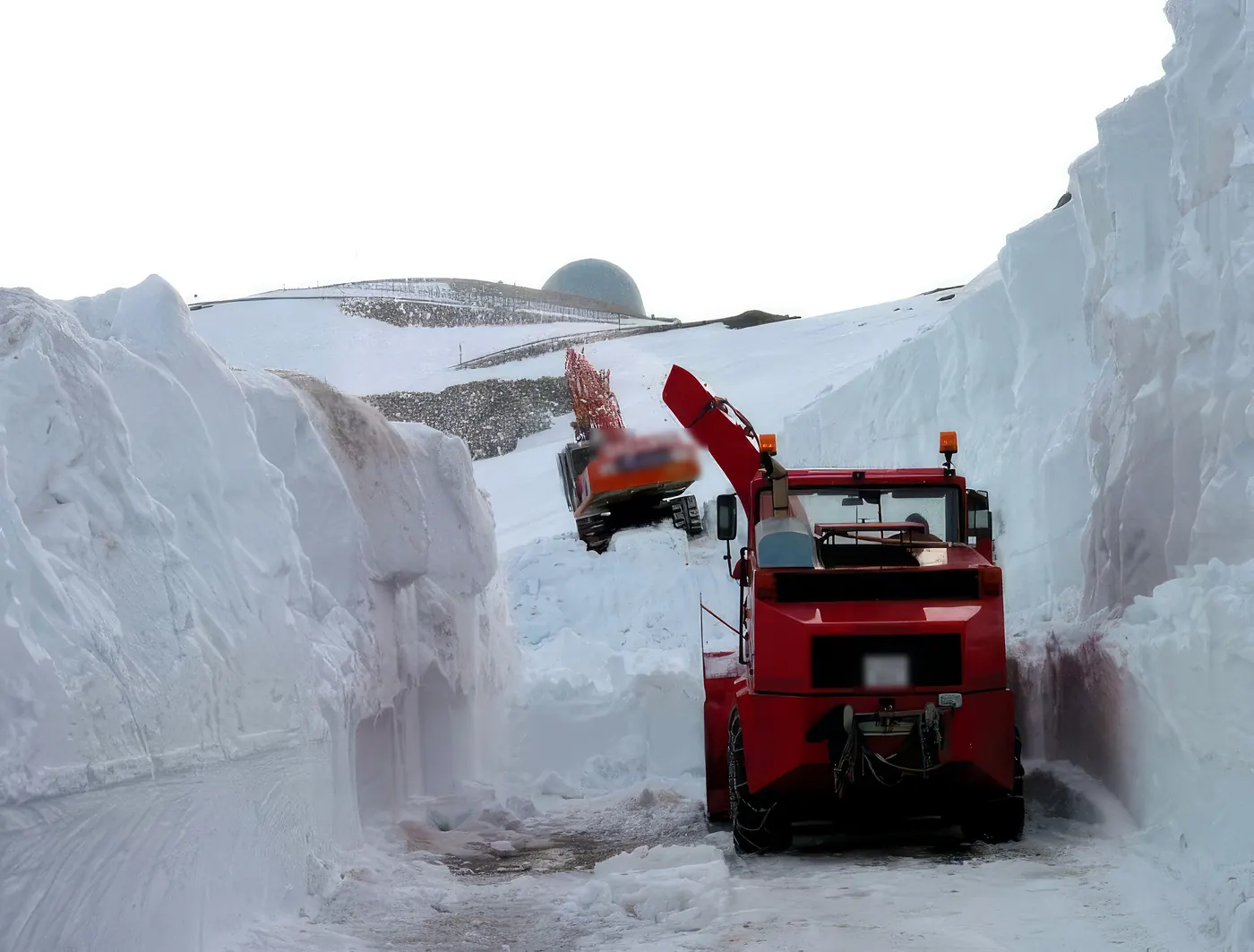 Fresadora quitanieves y retroexcavadora de Rallasa abriendo el acceso al EVA-12 entre paredes de nieve de varios metros