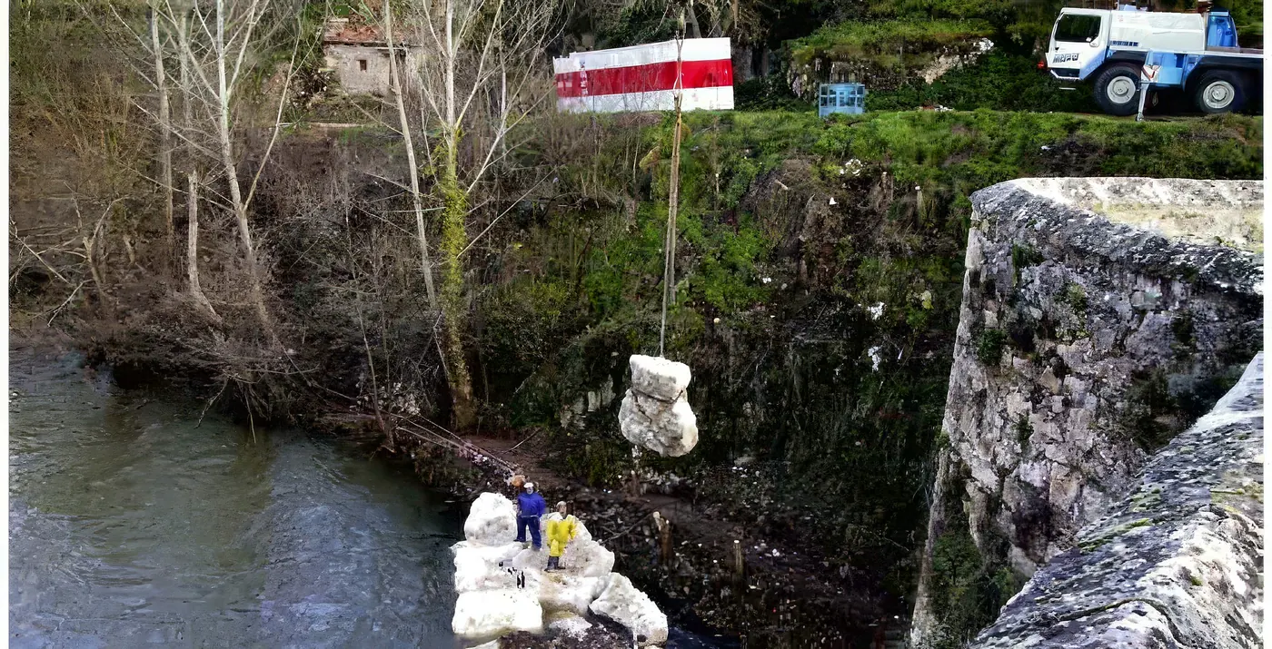 Grúa colocando una piedra de escollera en el río Ebro junto al puente de Pesquera